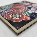Notebook featuring the Basket of Flowers textile design by Charles Rennie Mackintosh. The design depicts a stylised bouquet of brightly coloured flowers. The image shows a detail of the corner of the front cover.
