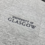 Embroidered 'University of Glasgow' logo on a gray fabric background