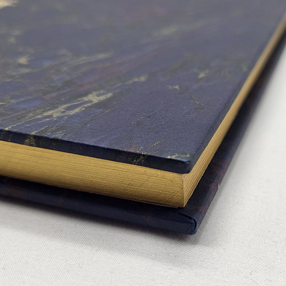 Close-up of a dark blue notebook with gold accents on a light gray background