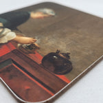 Angled view of drinks coaster featuring the painting A Lady Taking Tea by Jean Simeon Chardin (1735). The painting depicts a lady in elegant eighteenth-century dress seated at a red table with a teapot, teacup and saucer in front of her.