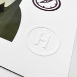 Close up image of the embossed H in a circle on the bottom right hand corner of the Lord Kelvin print. 