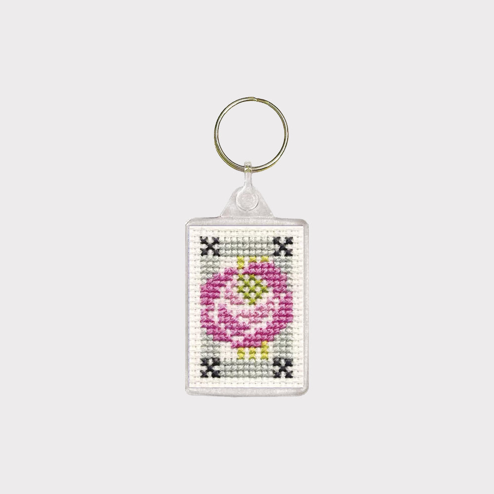Keychain with cross-stitched design of a pink flower on a white background
