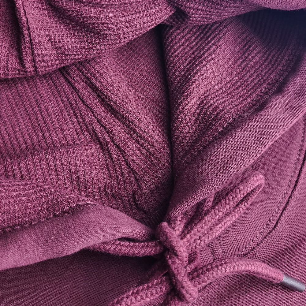 Close-up of a burgundy textured fabric with a knotted drawstring.