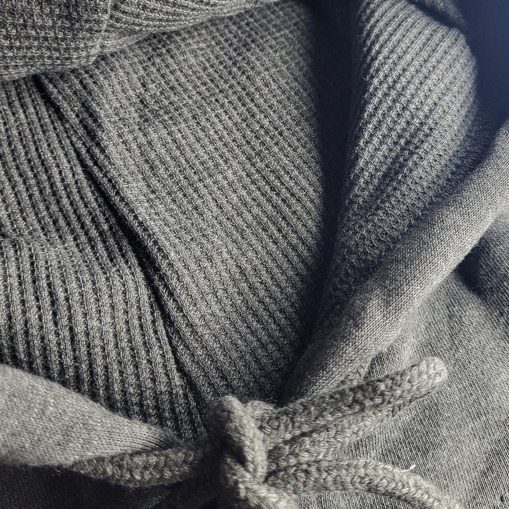 Close-up of a textured gray fabric with a hood and drawstring.