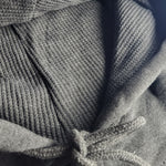 Close-up of a textured gray fabric with a hood and drawstring.