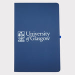University of Glasgow Navy A5 Pocket Notebook. The UofG crest is printed in white in the centre of the cover. The notebook has a navy closure band and a navy ribbon marker.