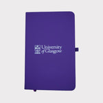 University of Glasgow Purple A6 Pocket Notebook. The UofG crest is printed in white in the centre of the cover. The notebook has a purple closure band and a purple ribbon marker.
