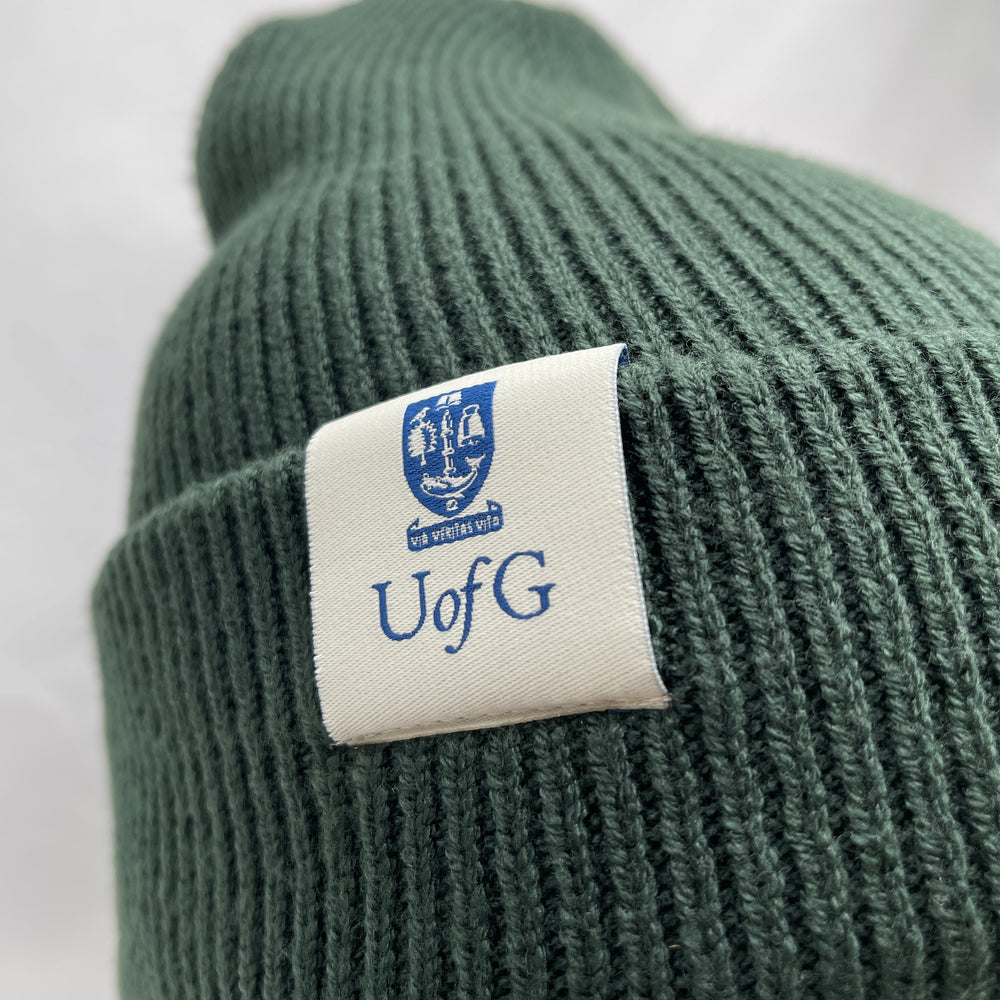 Green knit beanie with a label featuring 'UofG' on a white background
