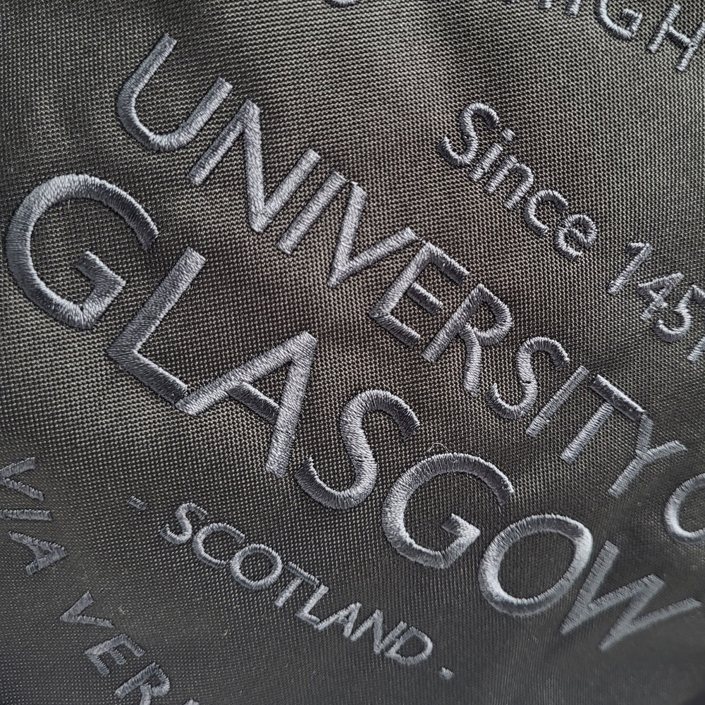 Embroidered text on a fabric background, including 'University of Glasgow' and 'Scotland'.
