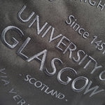 Embroidered text on a fabric background, including 'University of Glasgow' and 'Scotland'.