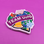 Magnet with 'TEAM UofG' text on a purple background