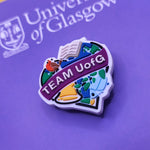 Colorful 'TEAM UofG' shoe charm on a purple background with 'University of Glasgow' text.