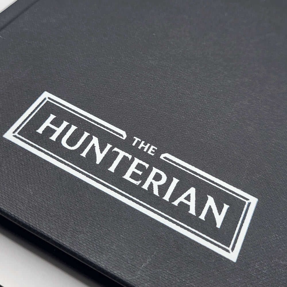 Close-up of a black book with 'The Hunterian' logo on a white background