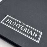 Close-up of a black book with 'The Hunterian' logo on a white background
