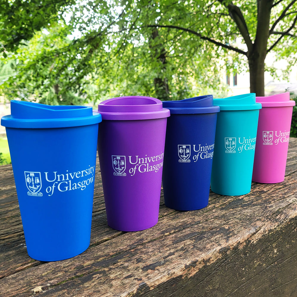 Five colorful tumblers with 'University of Glasgow' logo on a wooden surface outdoors.