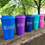 Five colorful tumblers with 'University of Glasgow' logo on a wooden surface outdoors.